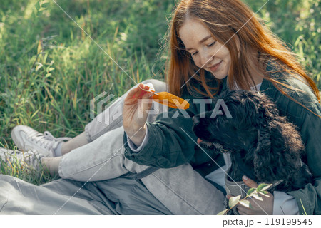 peaceful connection between nature, pets, and positive impact on mental health, red-haired woman, dog in park with ice cream 119199545