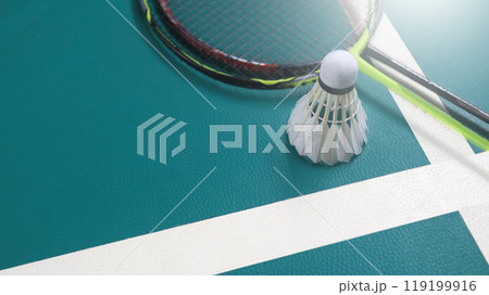 White badminton shuttlecocks and badminton rackets on green floor indoor badminton court. Concept for badminton competition and its lovers. White badminton shuttlecocks and badminton rackets on green floor indoor badminton court. Concept for badminton competition and its lovers. 119199916
