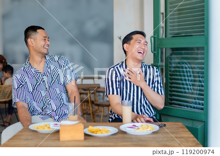 Two Friends Enjoying a Cheerful Moment in a Caf Setting 119200974