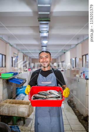 Fresh Catch A Smiling Fishmonger Welcoming Customers at a Vibrant Fish Market Fresh Catch A Smiling Fishmonger Welcoming Customers at a Vibrant Fish Market 119201379