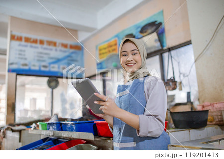 A Cheerful Smiling Woman Engaged with a Tablet in a Dynamic Food Business Environment 119201413
