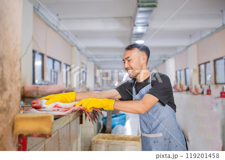 Hardworking individual managing fresh seafood handling in a processing facility 119201458