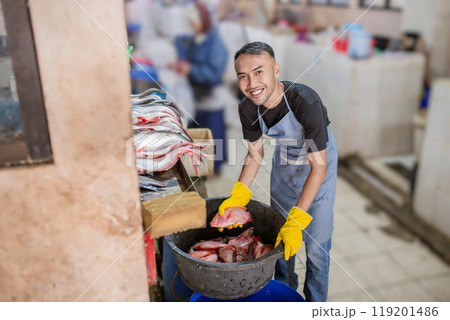 A Smiling Worker is Preparing Fresh, Delicious Seafood in a Busy Market Setting 119201486