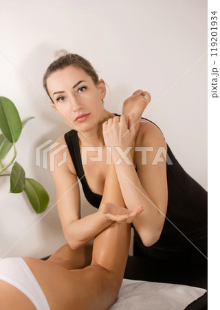Portrait of a masseuse giving a Thai massage to a patient on a massage table Portrait of a masseuse giving a Thai massage to a patient on a massage table 119201934