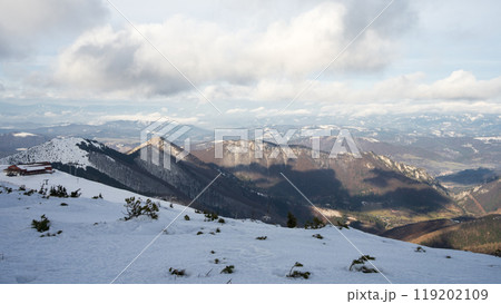 Early winter snowy landscape with mountains and ridgelines with thick clouds casting shadows on it Early winter snowy landscape with mountains and ridgelines with thick clouds casting shadows on it 119202109
