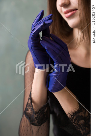 A beautiful woman in a black dress and blue leather gloves 119202457