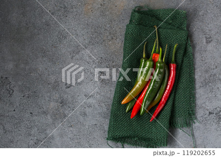 Several hot chili pepper pods on burlap, gray textured background Several hot chili pepper pods on burlap, gray textured background 119202655