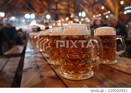 Oktoberfest beer mugs on a wooden table, warm lights in the background Oktoberfest beer mugs on a wooden table, warm lights in the background 119202951