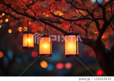 Glowing lanterns hanging from tree branches with autumn leaves. Glowing lanterns hanging from tree branches with autumn leaves. 119203019