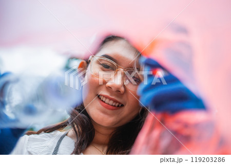low angle shot woman wearing glasses putting plastic bottle into plastic bag low angle shot woman wearing glasses putting plastic bottle into plastic bag 119203286