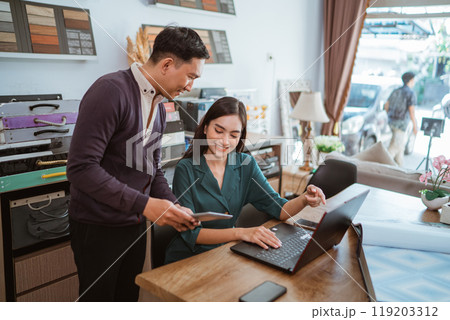asian shopkeeper pointing on her laptop while looking at the digital tablet asian shopkeeper pointing on her laptop while looking at the digital tablet 119203312