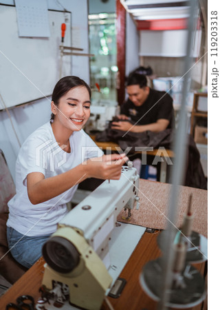 beautiful tailor setting the yarn at sewing machine while working 119203318