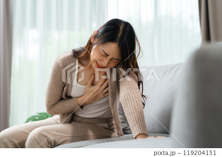A woman is holding her hand on her chest. She is in pain and she is suffering from a heart attack A woman is holding her hand on her chest. She is in pain and she is suffering from a heart attack 119204151