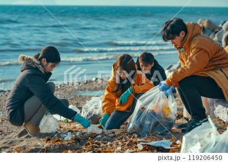 A group of people cleaning up trash on a beach wearing gloves during a sunny day near the ocean A group of people cleaning up trash on a beach wearing gloves during a sunny day near the ocean 119206450
