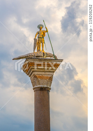 The San Teodoro Column stands majestically in Piazza San Marco, featuring a golden statue of St. Theodore on top, surrounded by vibrant skies that enhance the historic atmosphere. The San Teodoro Column stands majestically in Piazza San Marco, featuring a golden statue of St. Theodore on top, surrounded by vibrant skies that enhance the historic atmosphere. 119208262