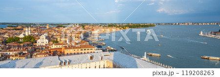 An expansive aerial view captures the iconic canals and historic buildings of Venice as the sun sets, illuminating the city with a warm glow and creating a picturesque atmosphere. An expansive aerial view captures the iconic canals and historic buildings of Venice as the sun sets, illuminating the city with a warm glow and creating a picturesque atmosphere. 119208263
