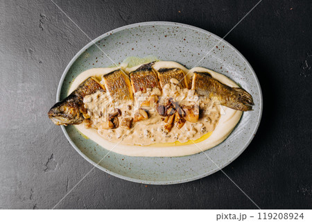 Whole roasted fish with creamy mushroom sauce and mashed potatoes on a ceramic plate Whole roasted fish with creamy mushroom sauce and mashed potatoes on a ceramic plate 119208924