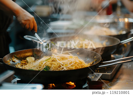 Noodles being cooked in wok on stove 119210801