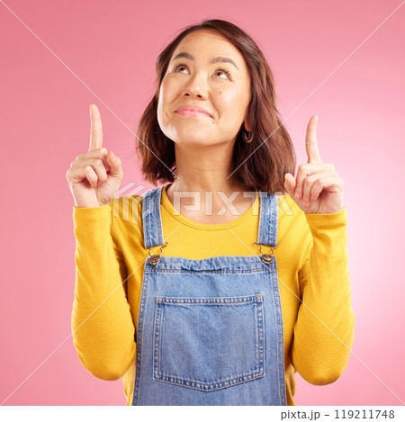 Smile, pointing and happy young woman in a studio for marketing, promotion or advertising. Happiness, confident and Asian female model with presentation finger gesture isolated by a pink background. 119211748