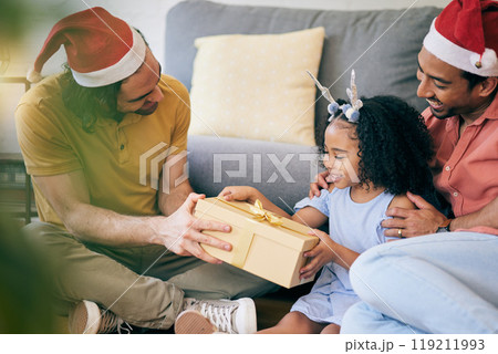 Gay, Christmas and a father with a gift for a child, celebration and holiday as a family. Smile, home and an lgbt man with a festive present for a girl kid in the living room of a house together 119211993
