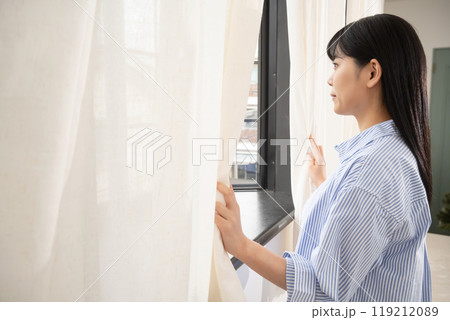 部屋の窓から外の景色を見る女性 部屋の窓から外の景色を見る女性 119212089