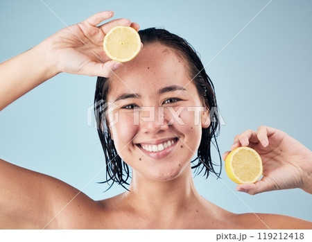 Portrait, smile or happy woman with lemon for skincare or beauty in studio on blue background. Dermatology, shine or Asian person with natural fruits, vitamin c or face glow for wellness or health 119212418