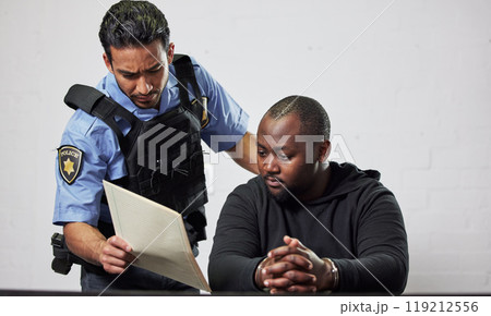 Policeman, criminal and handcuffs with documents for interrogation, question or arrest in fraud, scam or crime. Law enforcement officer talking to prisoner or thief with paperwork in prison or jail 119212556