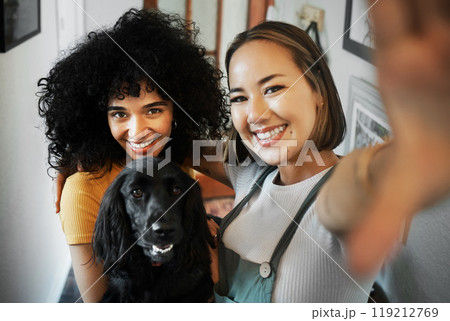 Smile, selfie and portrait of lesbian couple with dog in modern apartment bonding together. Love, happy and interracial young lgbtq women taking a picture and holding animal pet puppy at home. 119212769
