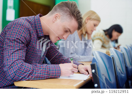 University student, desk and writing exam in classroom for education assessment for knowledge, diploma or scholarship. Men, woman and test in London lecture hall or study document, academy or college University student, desk and writing exam in classroom for education assessment for knowledge, diploma or scholarship. Men, woman and test in London lecture hall or study document, academy or college 119212951