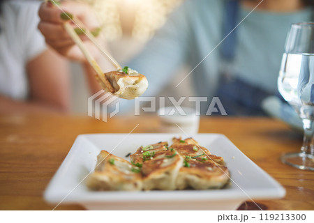 Table, plate and chopsticks with a dumpling at a restaurant for food, Asian culture or fine dining. Health, hungry and a person with dinner, eating lunch or enjoying a fried dish or cuisine at a cafe 119213300