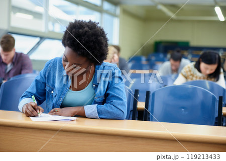 Writing, college and black woman student in classroom studying for test, exam or assignment. Education, university and African female person working on project with knowledge in lecture hall. 119213433