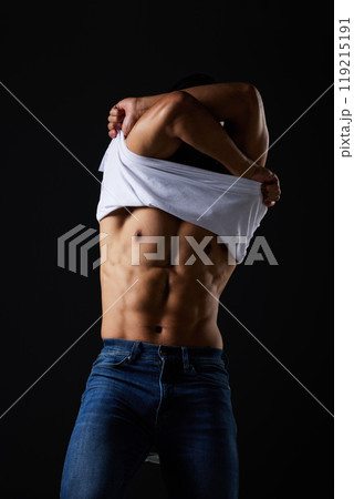 Fitness, body and man remove tshirt for exercise, wellness and workout in studio on black background. Bodybuilder, strong and person show stomach for motivation, muscle and lifestyle with pride 119215191