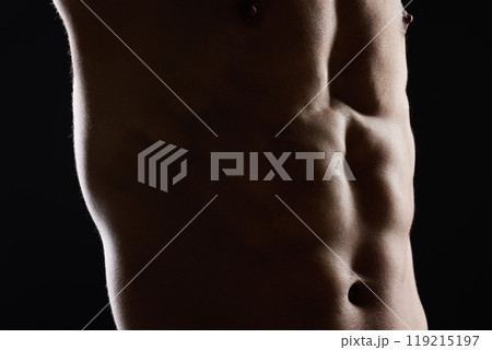 Man, abdomen and muscle in dark studio, shadow and wellness with health, strong and workout by black background. Bodybuilder guy, shirtless and stomach with skin, aesthetic and power in dark for art 119215197