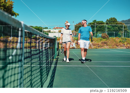 Let the games begin. Full length shot of two young tennis players talking while walking together outdoors on a tennis court. 119216509