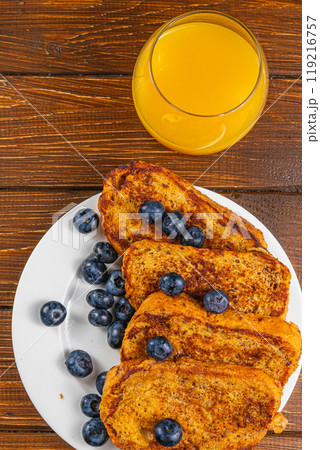 French toast on a white plate with blueberries and orange juice for breakfast French toast on a white plate with blueberries and orange juice for breakfast 119216757