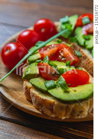 Avocado toast topped with tomato and green onion on a slice of carrot bread 119216772