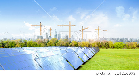 Solar panel farm on green field with cityscape background 119216975