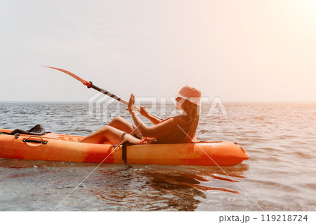 Kayaking Woman Ocean Sunset - Woman in a kayak paddling on the ocean at sunset, taking a selfie. 119218724