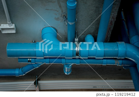 A bright blue pipes attached to a solid concrete wall 119219412