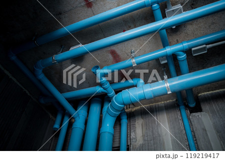 A bright blue pipes attached to a solid concrete wall 119219417
