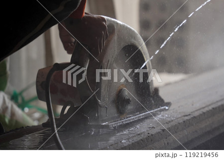 A builder using a circular saw to cut a large concrete piece A builder using a circular saw to cut a large concrete piece 119219456