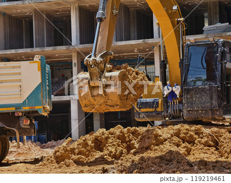 Excavator loads ground into a dump truck at a construction site 119219461