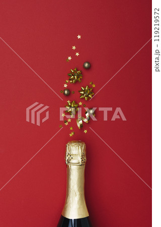 A champagne bottle with Christmas decorations on a red background 119219572