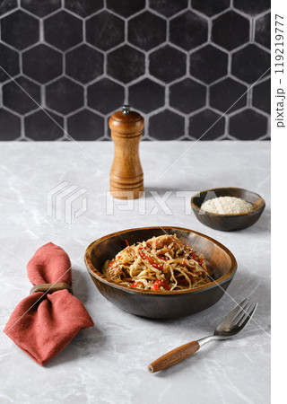 Delicious pasta with pulled beef dish served in a rustic bowl on a marble table with pepper and sesame Delicious pasta with pulled beef dish served in a rustic bowl on a marble table with pepper and sesame 119219777