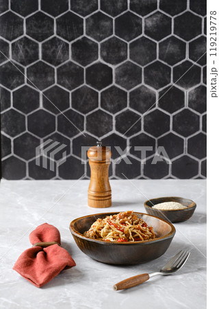 Delicious spaghetti with pulled beef and fresh ingredients served in a rustic bowl on a marble countertop 119219778