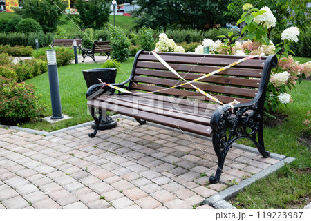 Park bench with caution tape in a garden setting. Park bench with caution tape in a garden setting. 119223987