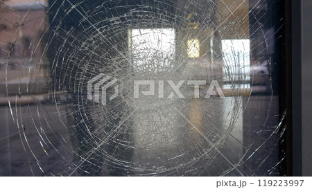 Reflections in a shop window cracked by a impact photographed from the street. Reflections in a shop window cracked by a impact photographed from the street. 119223997