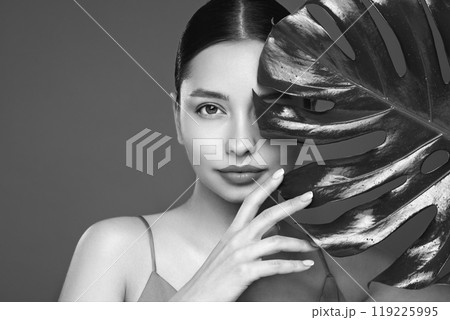 Close up woman face with green exotic leaf Close up woman face with green exotic leaf 119225995