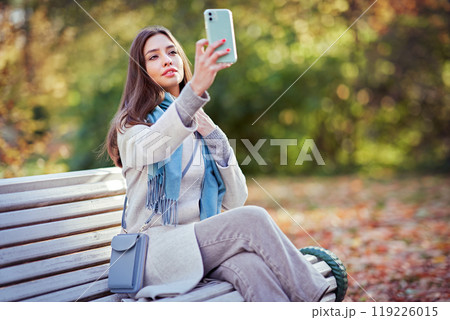 A girl with a smartphone takes photos in an autumn forest A girl with a smartphone takes photos in an autumn forest 119226015