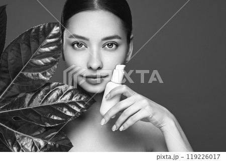 Close up woman face with green exotic leaf 119226017